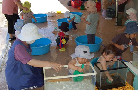 プラスチックのたらいに水をはって遊ぶ0歳児～2歳児クラスの園児