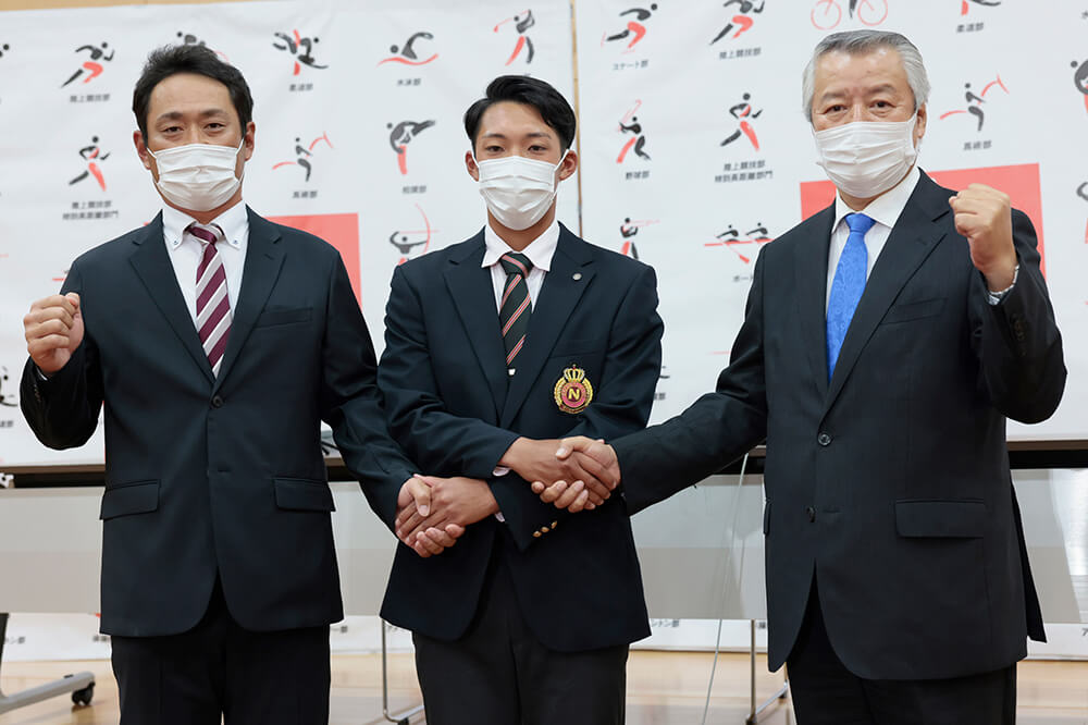 野球部の山中晴之副部長（右）、片岡昭吾監督（左）と握手を交わす赤星選手。