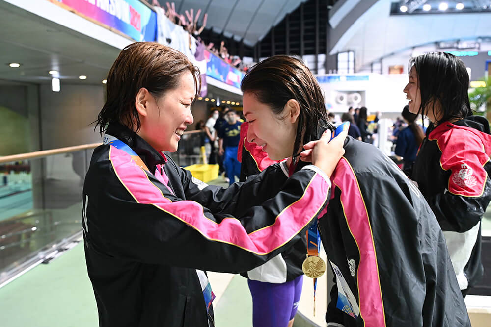 練習パートナーとしても切磋琢磨してきた持田選手から金メダルを掛けてもらう池江選手。