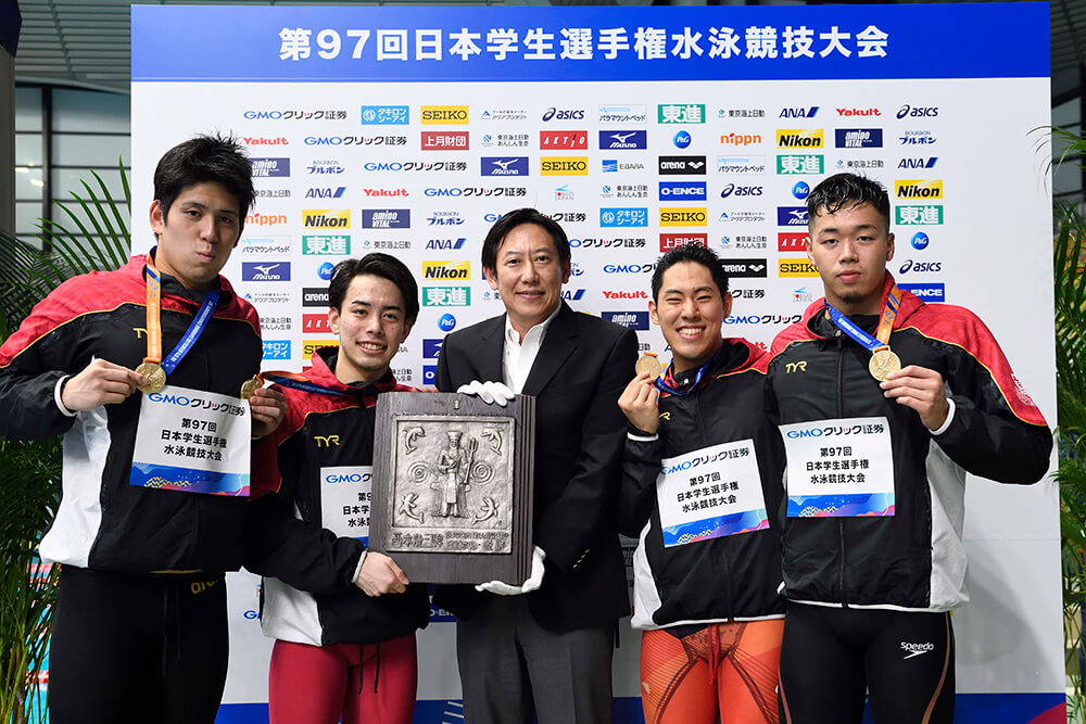 日本水泳連盟の鈴木大地会長から西本杯を授与されたリレーメンバー。左から石崎選手、尾崎選手、鈴木会長、本多選手、吉田選手。