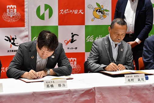 署名を行う高橋勝浩市長（左）と木村政司副学長（競技スポーツ担当）（右）